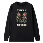 A black oversized long sleeve tee with the It's OK To Be A Little Odd graphic printed large on the front.