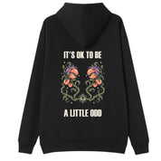 A black oversized hoodie shown from the back, with the It's OK To Be A Little Odd graphic printed large across the back.