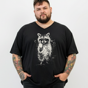A man with a beard and tattooed arms wearing a black V-neck t-shirt with a white distressed raccoon graphic on the front, standing against a plain white background.