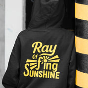 Black hoodie with yellow text 'Ray of f*ing Sunshine' on the back, worn by a person.