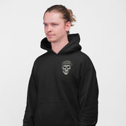 Person wearing a black hoodie with a skull and cap design on a light gray background