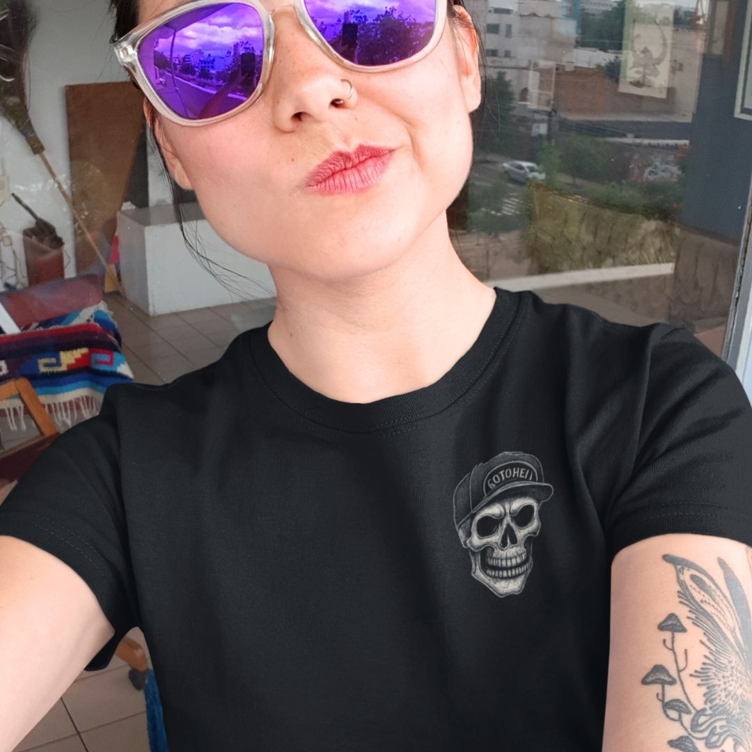 Person wearing a black t-shirt with a skull design and purple sunglasses, indoors.