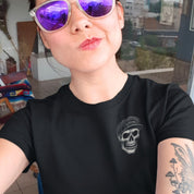 Person wearing a black t-shirt with a skull design and purple sunglasses, indoors.