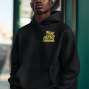 Person wearing a black hoodie with yellow text in an urban setting