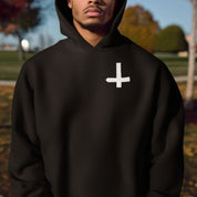 Person wearing a black hoodie with a white symbol outdoors