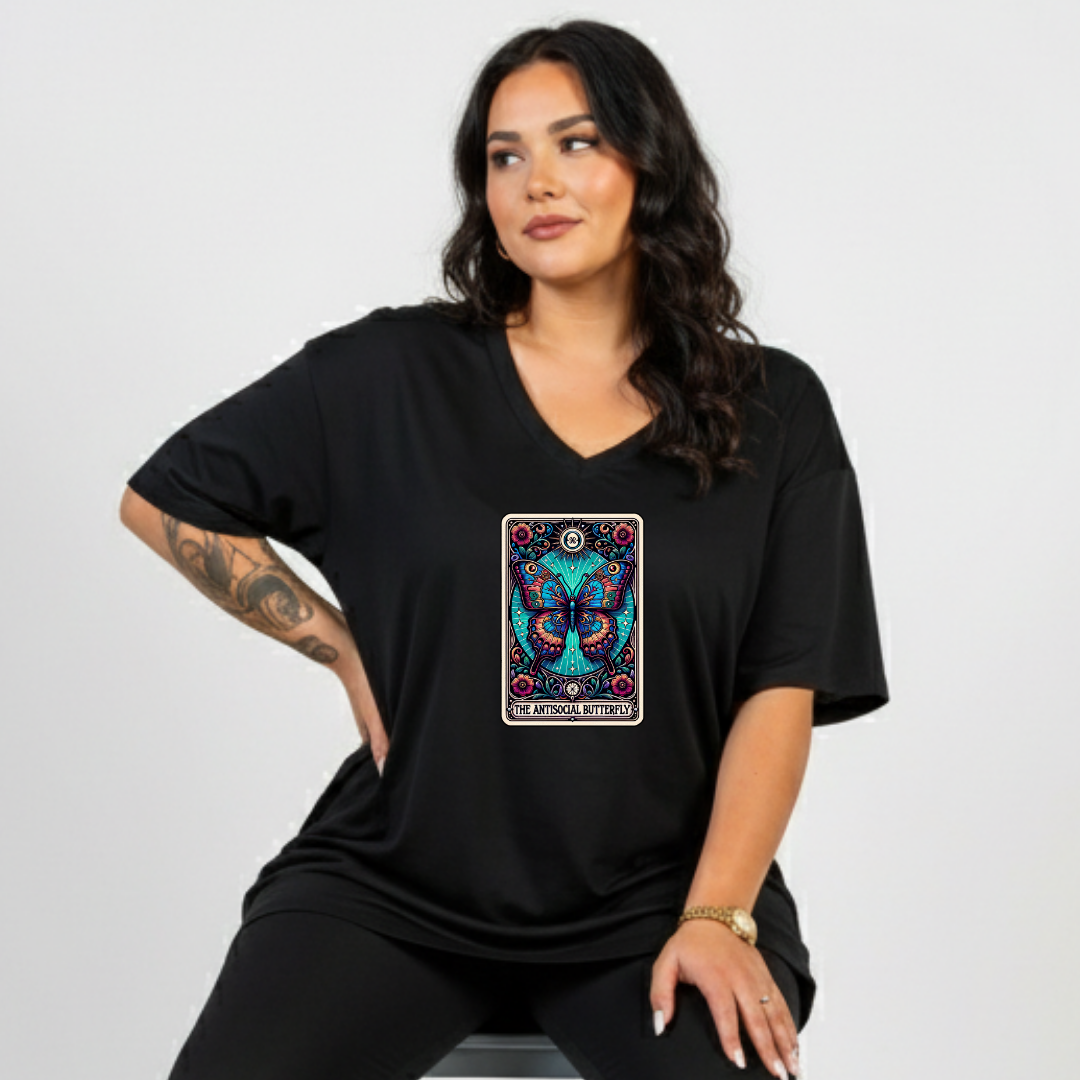 Woman wearing a black t-shirt with a colorful butterfly design on a plain background