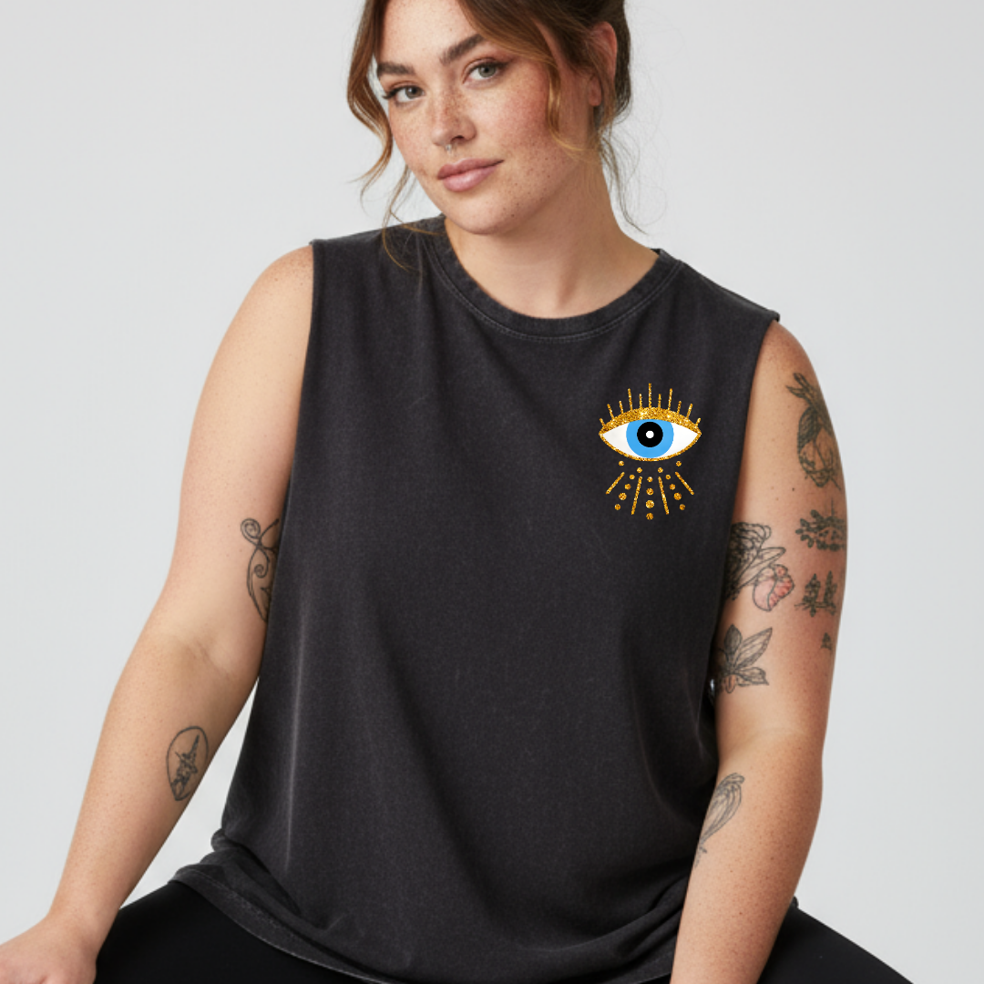 Woman wearing a black sleeveless shirt with an eye design on a plain background