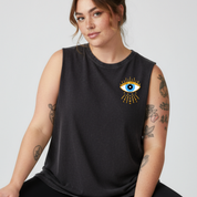 Woman wearing a black sleeveless shirt with an eye design on a plain background