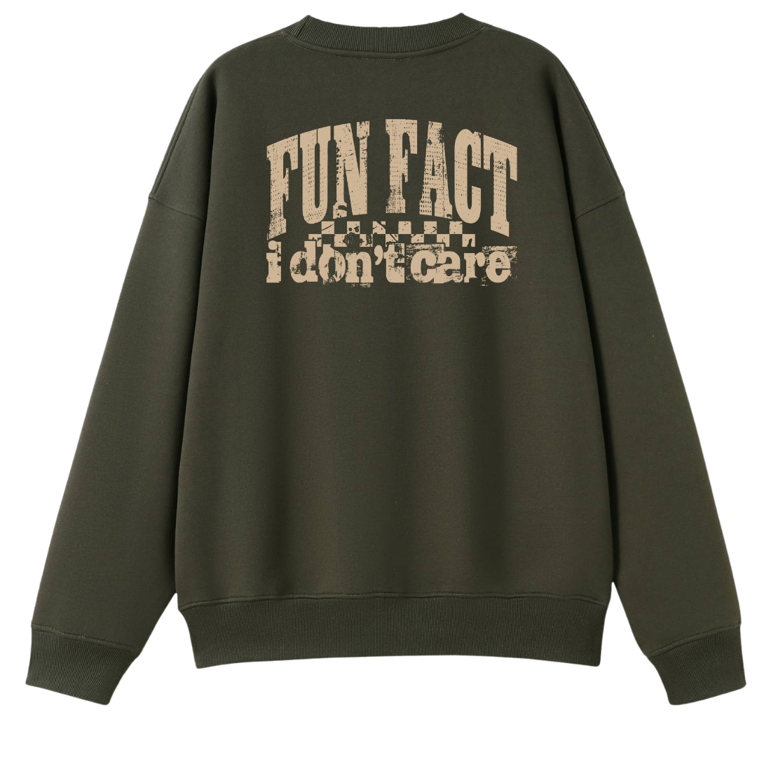 An olive green crewneck sweatshirt shown from the back, featuring a distressed beige graphic print that reads 'FUN FACT i don't care' with a small flag design above it.