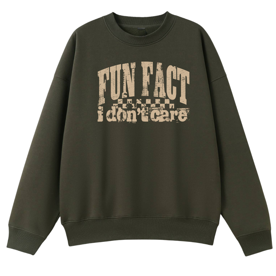 An oversized crewneck sweatshirt in dark olive green with a distressed beige graphic on the chest that reads 'FUN FACT I don't care' with a checkerboard pattern.