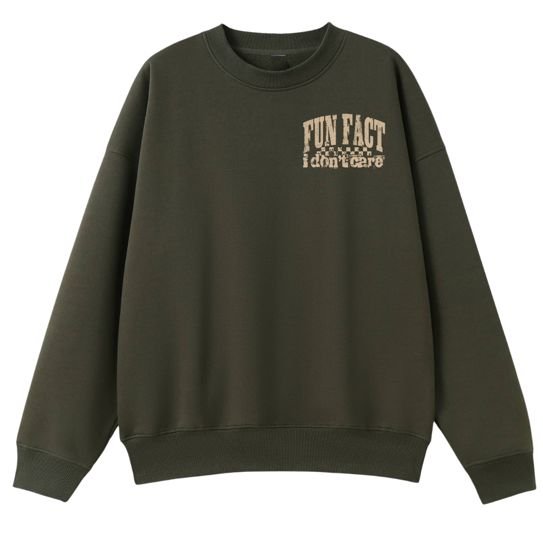 An oversized crewneck sweatshirt in dark olive green with a beige graphic text print on the left chest reading 'FUN FACT i don't care' with small stars, shown against a plain white background.