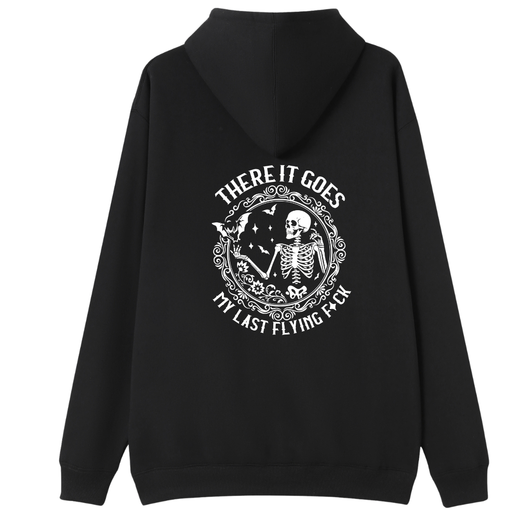 A black pullover hoodie shown from the back, featuring a large white graphic print of a skeleton inside an ornate circular frame with the text 'THERE IT GOES' above and 'MY LAST FLYING F*CK' below.