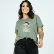 Woman wearing a green t-shirt with a Christmas-themed graphic and text.