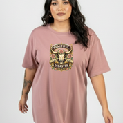 Person wearing a dusty pink t-shirt with a graphic design on a plain background