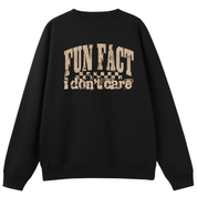 A black crewneck sweatshirt shown from the back, featuring a distressed beige graphic print that reads 'FUN FACT i don't care' with a small flag motif.
