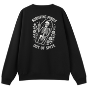 A black crewneck sweatshirt shown from the back, featuring a large white graphic print of a skeleton sitting in a coffin with the text 'SURVIVING PURELY OUT OF SPITE' and floral details.
