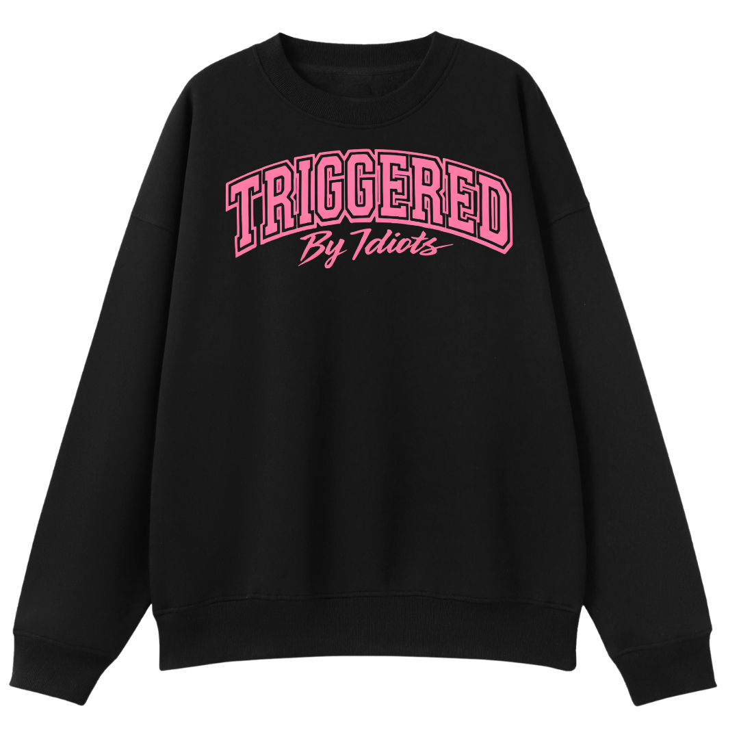 A black crewneck sweatshirt with 'TRIGGERED By Idiots' printed in pink across the chest, displayed on a clean white background.