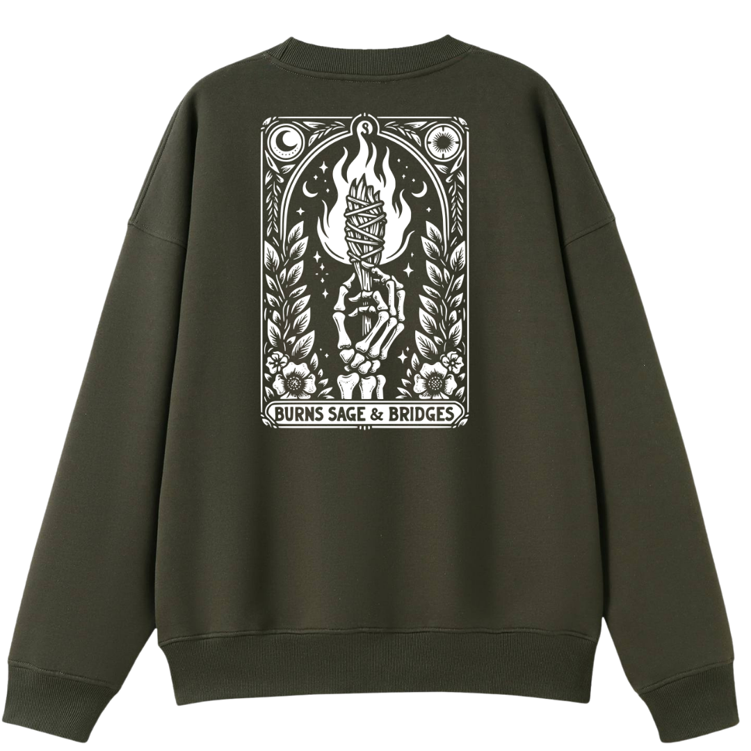 An olive green crewneck sweatshirt shown from the back, featuring a large white graphic print on the back with a hand holding a burning book and the text 'BURNS SAGE & BRIDGES'.