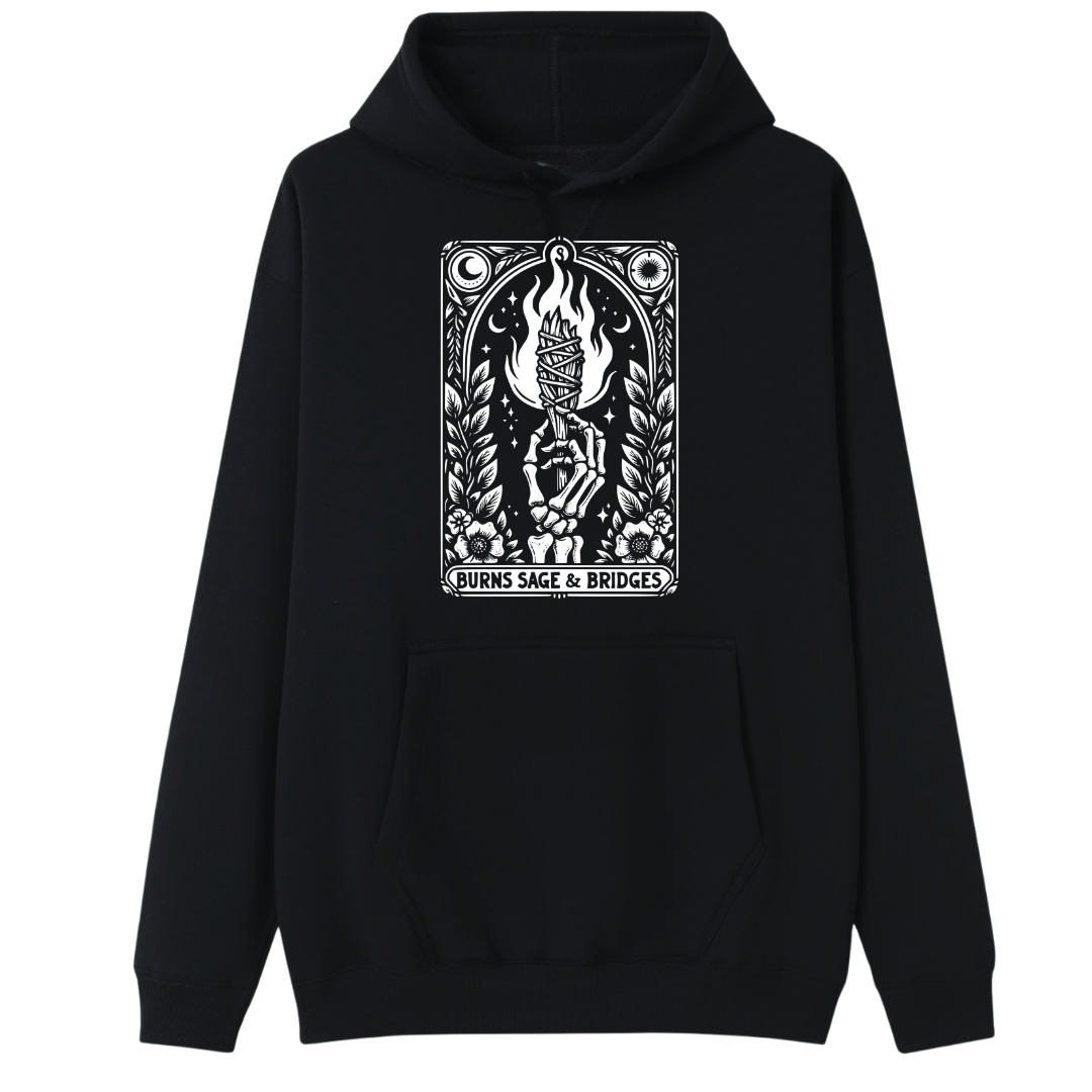 A black pullover hoodie with a white graphic print on the chest depicting a hand holding a burning candle, surrounded by flames, leaves, and the text 'BURNS SAGE & BRIDGES'.