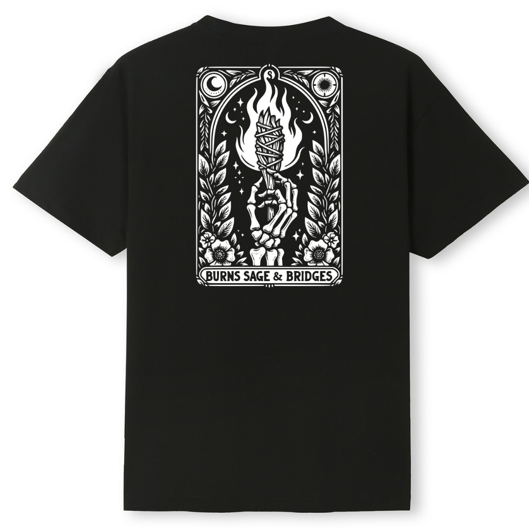 A black short-sleeve t-shirt shown from the back, featuring a large white graphic print of a tarot card design with a skeleton holding a flaming torch and the text 'BURNS SAGE & BRIDGES' at the bottom.