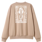 A beige crewneck sweatshirt shown from the back, featuring a large white graphic print of a hand holding a flaming torch surrounded by decorative elements and the text 'BURNS SAGE & BRIDGES'.