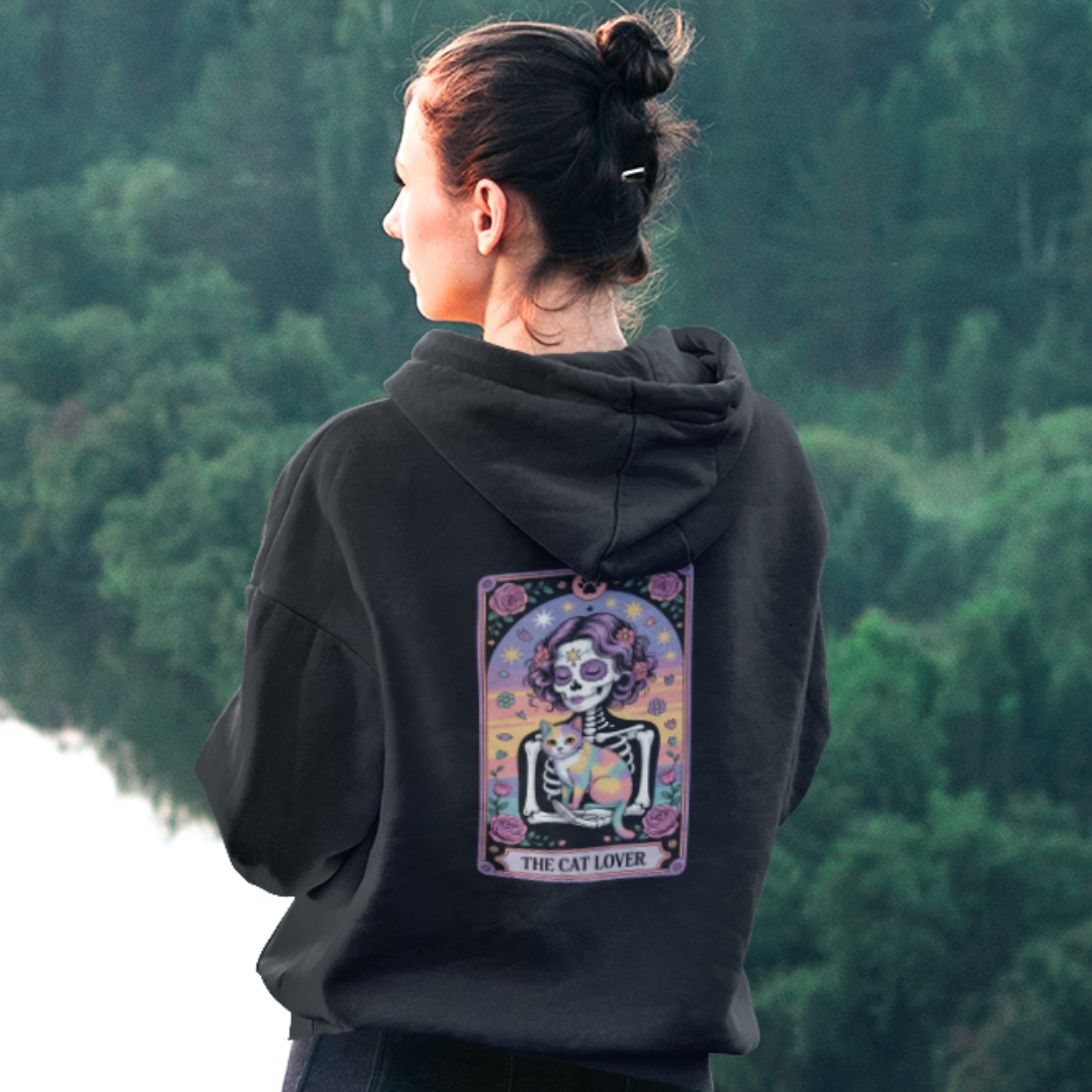 Person wearing a black hoodie with a colorful graphic on the back, standing in a forest.
