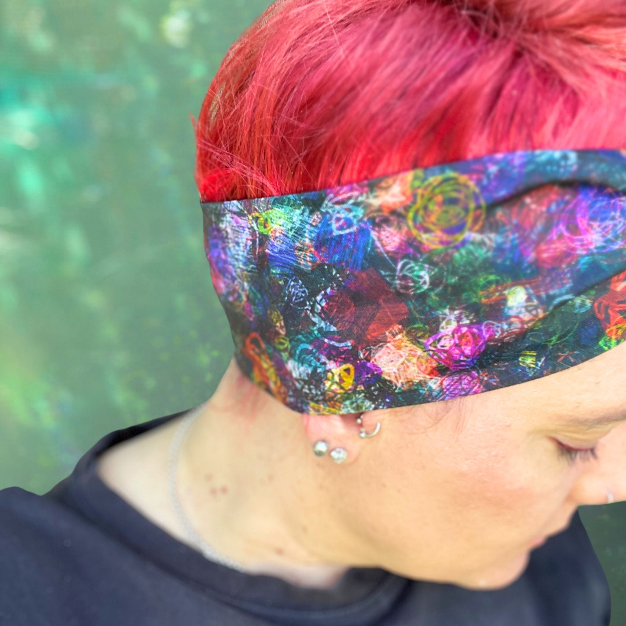 a colorful wire headwrap with a vibrant, abstract pattern. The headwrap is tied at the top, giving it a playful and chic bow effect.