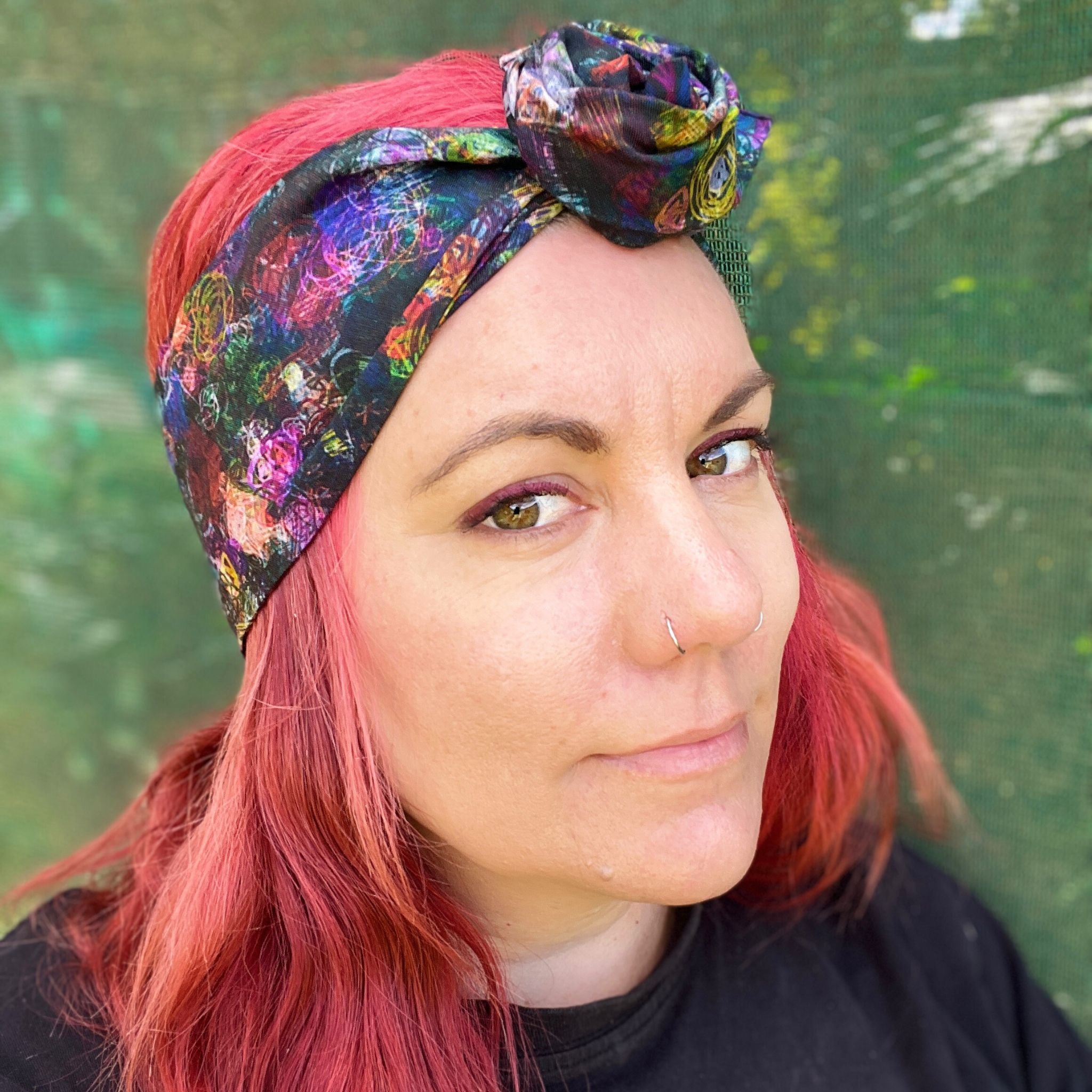 a colorful wire headwrap with a vibrant, abstract pattern. The headwrap is tied at the top, giving it a playful and chic bow effect.