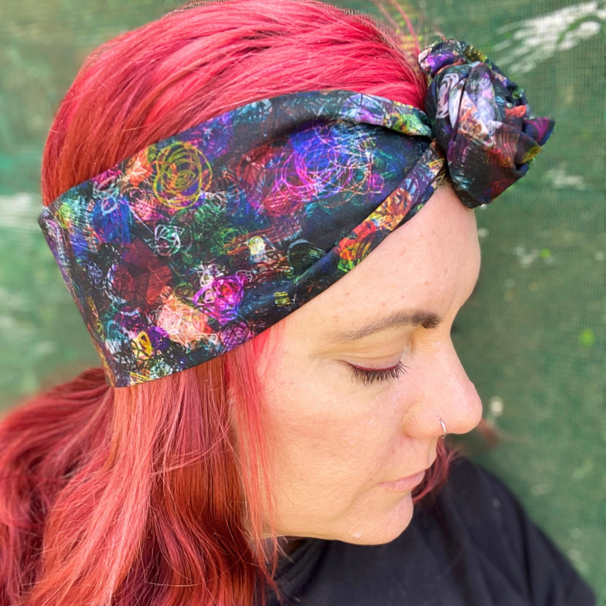 a colorful wire headwrap with a vibrant, abstract pattern. The headwrap is tied at the top, giving it a playful and chic bow effect.