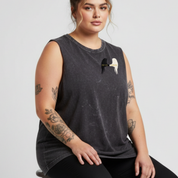 Woman wearing a dark gray sleeveless shirt with a graphic design on a light gray background