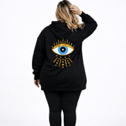 Black hoodie with an eye design on the back worn by a person against a white background