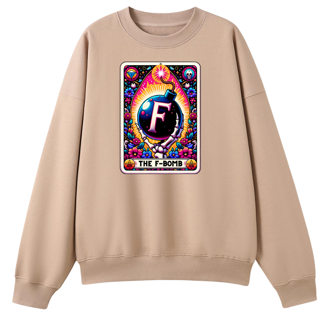 A beige crewneck sweatshirt featuring a colorful graphic print on the chest. The graphic is styled like a vintage tarot card labeled 'THE F-BOMB' with a bomb illustration and the letter 'F' in the center.