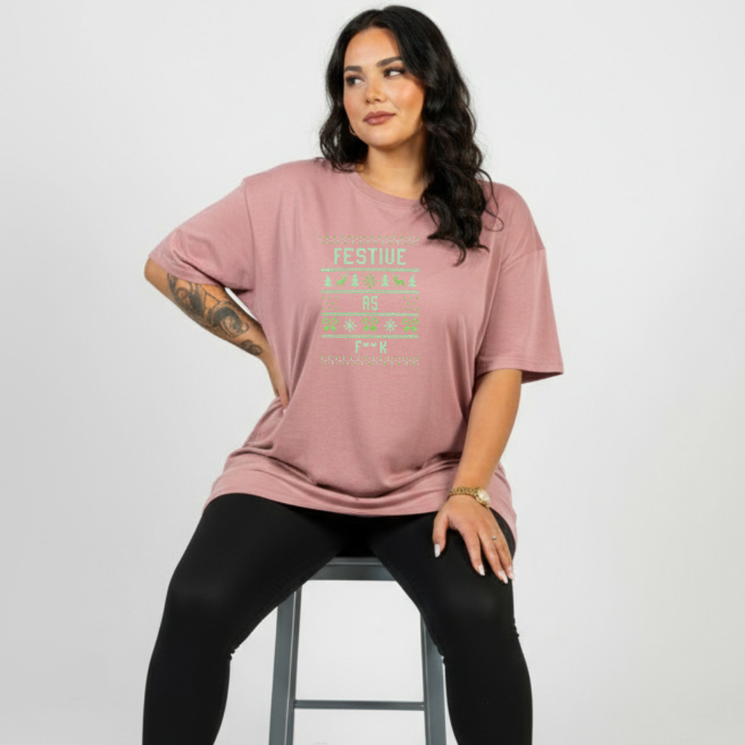 Woman wearing a pink t-shirt with text, sitting on a stool against a plain background
