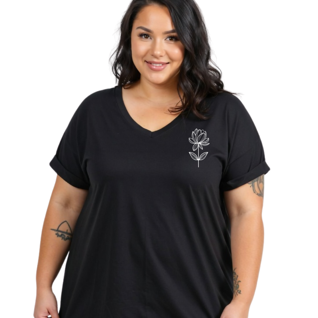 A woman wearing a black short-sleeve V-neck t-shirt with a small white line-art flower graphic on the left chest, photographed against a plain white background.