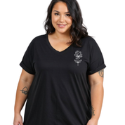 A woman wearing a black short-sleeve V-neck t-shirt with a small white line-art flower graphic on the left chest, photographed against a plain white background.