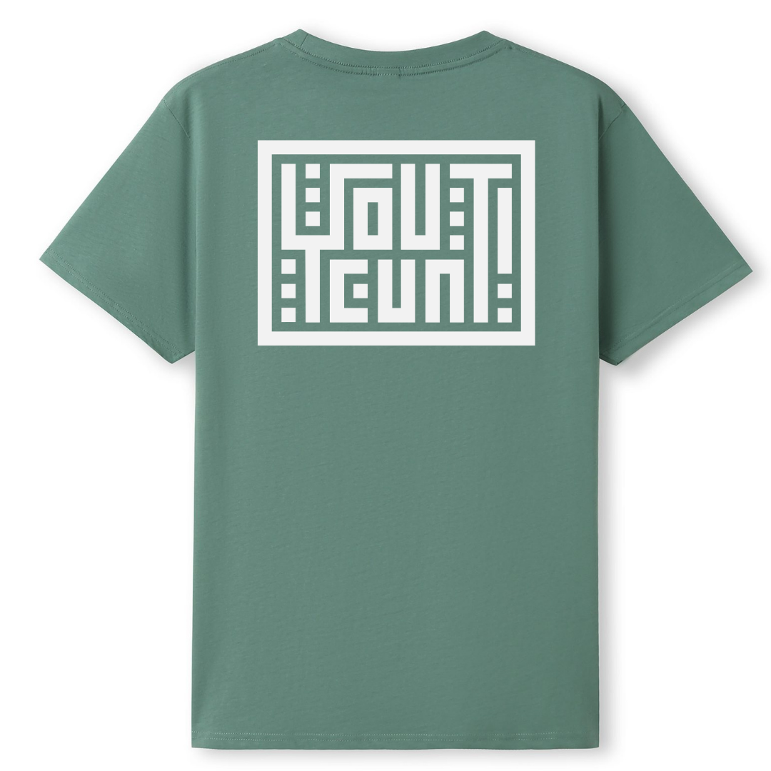 A sage green short-sleeve t-shirt shown from the back, featuring a large white geometric graphic with the word 'OUTCAST' in stylized block letters inside a white rectangular border.