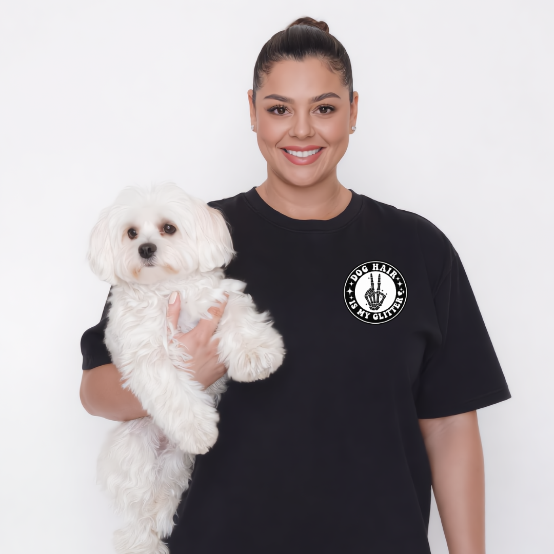Woman holding a white dog wearing a black t-shirt with a logo on a white background