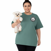 Woman wearing a green t-shirt with a logo, holding a small white dog on a white background