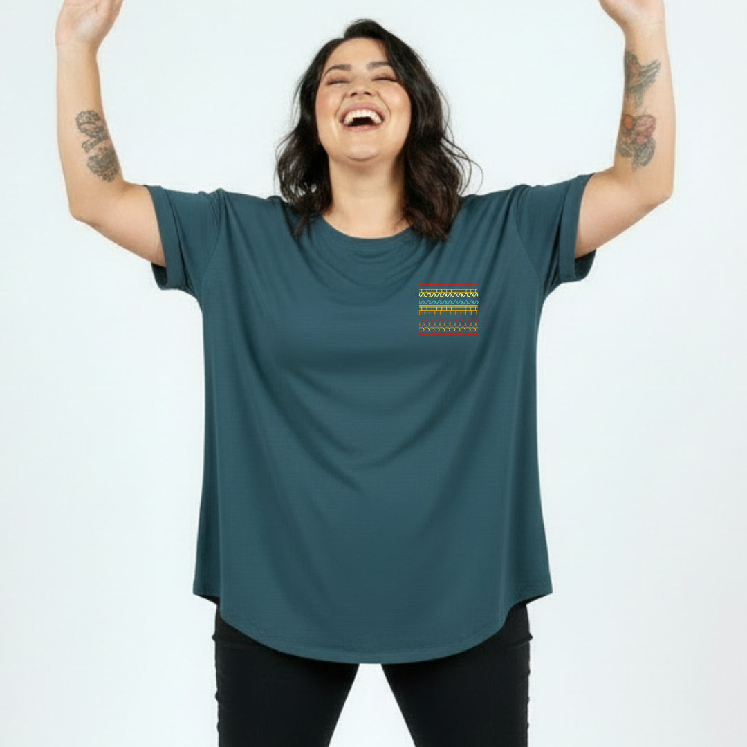 Person wearing a teal t-shirt with a colorful pocket design on a white background