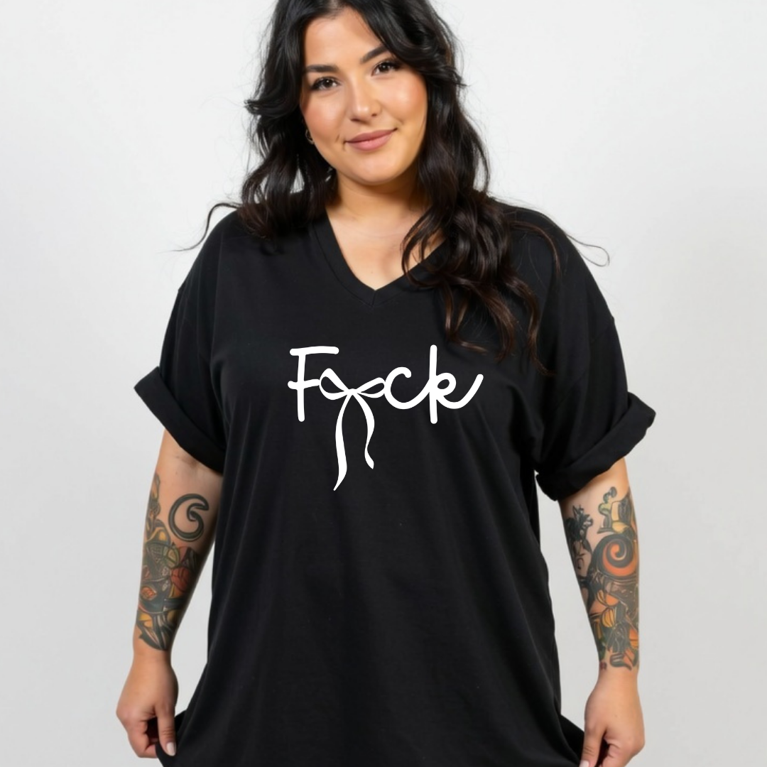 A woman modeling a black oversized V-neck t-shirt with the word 'Fuck' printed in white script across the chest, set against a plain light gray background.