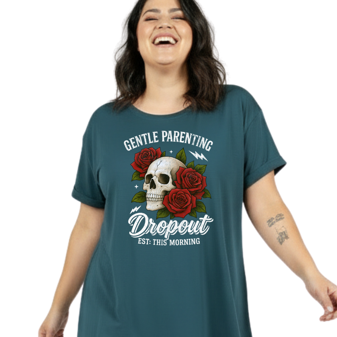 A woman wearing a dark teal graphic t-shirt with a skull, red roses, and the text 'GENTLE PARENTING Dropout EST: THIS MORNING' on a plain white background.