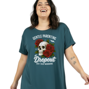 A woman wearing a dark teal graphic t-shirt with a skull, red roses, and the text 'GENTLE PARENTING Dropout EST: THIS MORNING' on a plain white background.