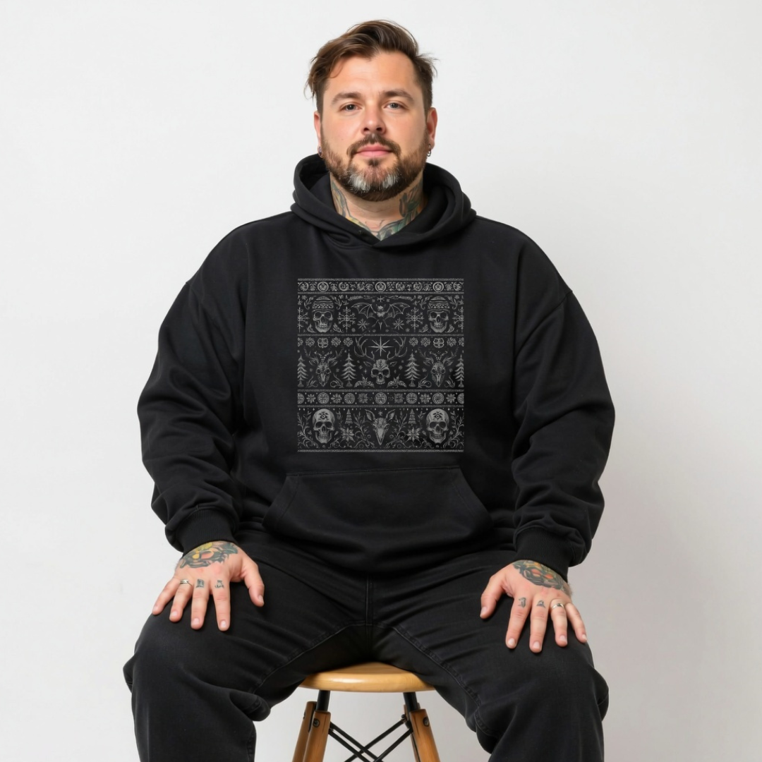 Man wearing a black hoodie with a pattern sitting on a stool against a white background