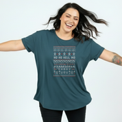 Woman wearing a teal t-shirt with a festive design and text on a light blue background