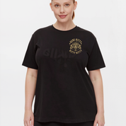 A woman modeling a black short-sleeve t-shirt with a gold graphic on the left chest that reads 'HERE KITTY KITTY KITTY' around a kitten illustration. The word 'SHAPES' is printed in a subtle, tonal black font across the center chest.