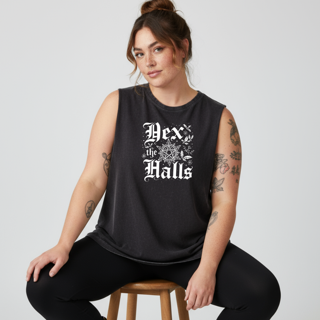 Woman wearing a black sleeveless shirt with 'Dex the Halls' text, sitting on a stool against a plain background.