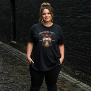 Person wearing a black t-shirt with a graphic design against a dark brick wall.