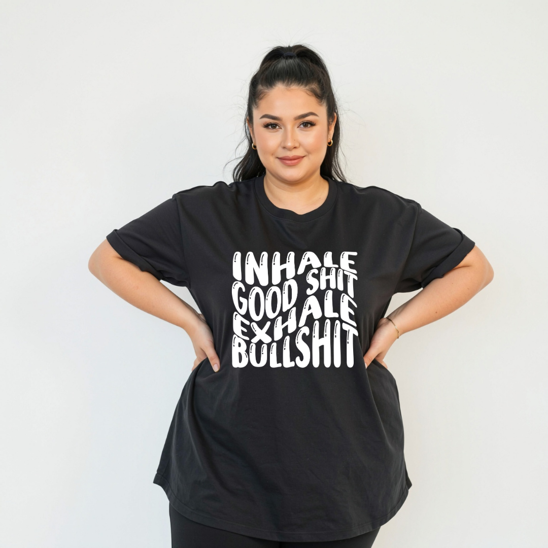 Woman wearing black oversized graphic tee with Inhale Good Shit Exhale Bullshit bold stacked white text print, plus size Australian streetwear by Bae Bands