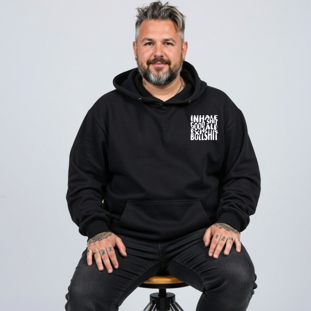 Front view of a man wearing black Inhale Good Shit Exhale Bullshit hoodie, relaxed fit, bold wavy white typography, plus size Australian streetwear by Bae Bands