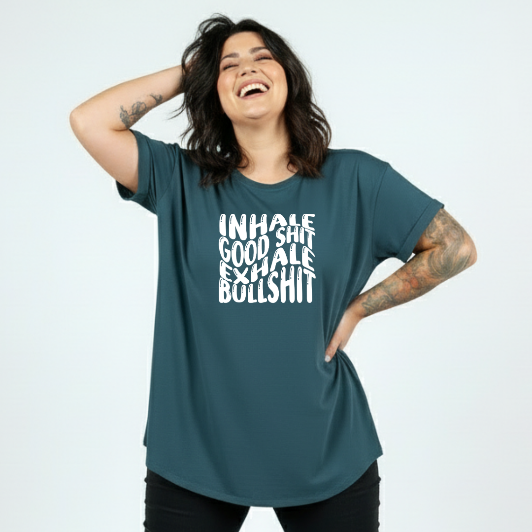 Woman wearing teal oversized graphic tee with Inhale Good Shit Exhale Bullshit bold stacked white text print, plus size Australian made streetwear by Bae Bands